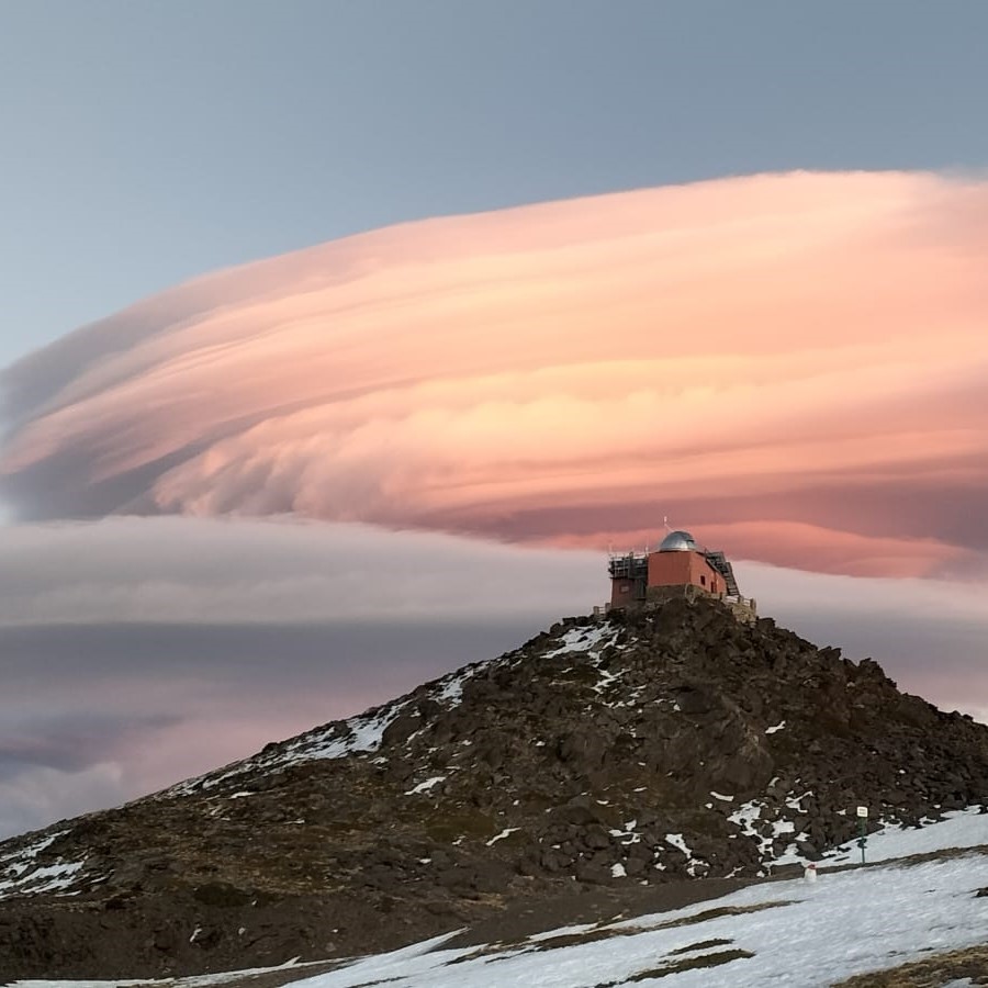 Observatorio de Sierra Nevada al atardecer con nubes en tonos rosados.